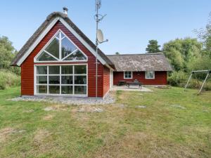 a red house with a large window on a yard at Holiday Home Jenna - 1-4km from the sea in Western Jutland in Vesterhede