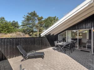een patio met een tafel en stoelen en een hek bij Holiday Home Thera - 2-8km from the sea in Western Jutland by Interhome in Bolilmark