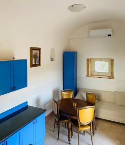 - une salle à manger avec des armoires bleues, une table et des chaises dans l'établissement Domus Agricolae Corallina, à Torre del Greco