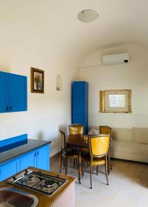 cocina con armarios azules, mesa y sillas en Domus Agricolae Corallina, en Torre del Greco