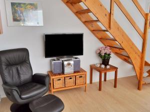 uma sala de estar com uma cadeira e uma televisão de ecrã plano em Apartment Jasna - 2-3km from the sea in Western Jutland by Interhome em Sønderby