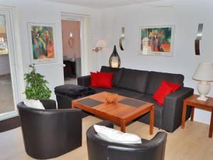 uma sala de estar com um sofá preto e almofadas vermelhas em Apartment Jasna - 2-3km from the sea in Western Jutland by Interhome em Sønderby