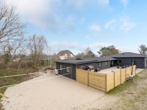 a black house with a wooden fence in front of it at Holiday Home Christiern - 4-5km from the sea by Interhome in Kongsmark
