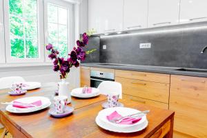 a kitchen with a wooden table with plates and flowers at Apartments Mala Vila in Rab