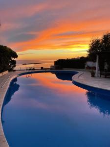a swimming pool with a sunset in the background at Villa con Piscina Privata fronte Spiaggia in Santa Marinella