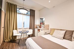 a bedroom with a bed and a table and a kitchen at Les cles du 27 Paris in Paris