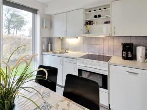 una cocina con armarios blancos y una mesa con sillas. en Apartment Tinna - 2-3km from the sea in Western Jutland by Interhome, en Sønderby