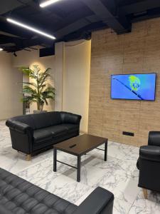 a living room with a couch and a tv on a wall at Mega Hostel in Almaty