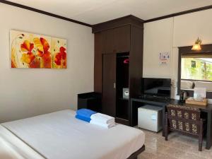 a bedroom with a bed and a desk and a painting at Golden Bay Cottage - SHA Extra Plus in Ko Lanta