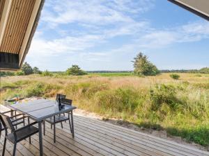 a table and chairs on a deck with a view of a field at Holiday Home Allin - 1km from the sea in Western Jutland by Interhome in Mølby