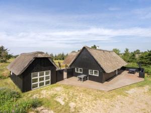 a large black house with a thatched roof at Holiday Home Allin - 1km from the sea in Western Jutland by Interhome in Mølby