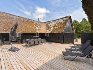 a deck with chairs and a building with a roof at Holiday Home Allin - 1km from the sea in Western Jutland by Interhome in Mølby