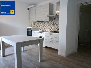a kitchen with white cabinets and a table in it at Residenza Nettuno in Chioggia