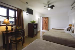 a bedroom with two beds and a desk with a lamp at Hotel Mozonte in Managua