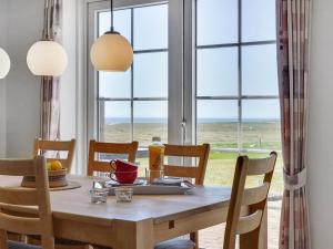 a dining room with a table and chairs with a view of the ocean at Holiday Home Langsom - 100m from the sea in Western Jutland by Interhome in Havneby