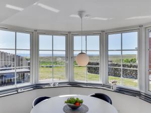 a dining room with windows and a table and chairs at Holiday Home Langsom - 100m from the sea in Western Jutland by Interhome in Havneby