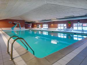a large swimming pool with blue water in a building at Apartment Mirija - 2-3km from the sea in Western Jutland by Interhome in Havneby