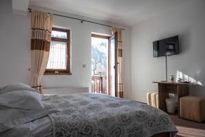 a bedroom with a bed and a television and a window at Pensiunea Andaluz in Poiana Micului