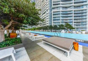 a pool with white benches next to a large building at 2 Bedroom with stunning views at the W residences in Miami
