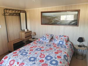 a bedroom with a bed with a blue and red comforter at Agréable Tiny house à la campagne in Coulombs
