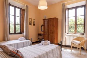 2 camas en una habitación con 2 ventanas en Il Vecchio Mulino Toscana, en Radicondoli