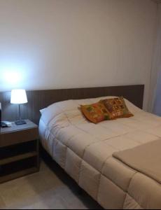1 dormitorio con 1 cama y mesita de noche con lámpara en La Moradita en Belén de Escobar