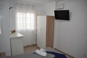 Kleines weißes Zimmer mit einem Bett und einem Kühlschrank. in der Unterkunft La casita de ¨Pueblo Rocio¨ in Torre del Mar