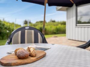 een houten snijplank met twee broodjes op een tafel bij Holiday Home Elise - 800m from the sea in Western Jutland by Interhome in Lakolk
