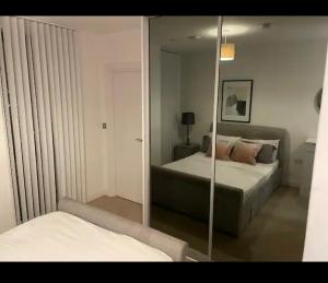 Luxurious 2 bedroom apartment in Canary Wharf في لندن: مرآة في غرفة النوم مع سرير