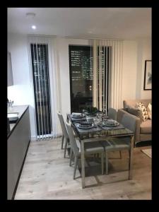 Luxurious 2 bedroom apartment in Canary Wharf في لندن: غرفة معيشة مع طاولة مع كراسي وأريكة
