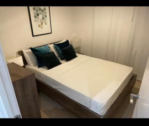 Luxurious 2 bedroom apartment in Canary Wharf في لندن: سرير بشرشف ووسائد بيضاء في الغرفة