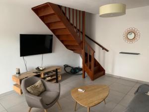 a living room with a television and a stair case at La Duchesse - T3 Duplex à St-Gilles-Les-Bains in Saint-Gilles les Bains