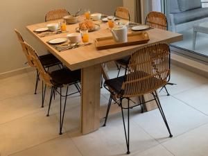 una mesa de madera con sillas alrededor con comida. en La Duchesse - T3 Duplex à St-Gilles-Les-Bains en Saint-Gilles-les-Bains