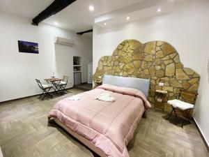 a bedroom with a pink bed and a stone wall at Trilogy in La Spezia