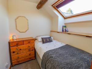 a bedroom with a bed and a dresser and a window at Trickett Gate Cottage in Castleton