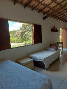 a bedroom with two beds and a large window at Chale Trilha Das Aguas in Rio de Contas