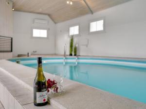 a bottle of wine and a glass next to a swimming pool at Holiday Home Madalena - 2-8km from the sea in Western Jutland in Toftum