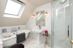 La salle de bains est pourvue d'une baignoire, d'un lavabo et d'une douche. dans l'établissement Ivy Cottage B&B, à Killarney