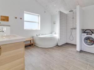 a bathroom with a tub and a washing machine at Holiday Home Minke - 2-2km from the sea in Western Jutland in Bolilmark