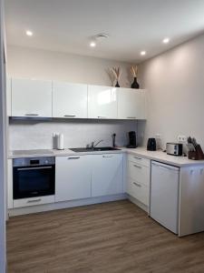 eine weiße Küche mit weißen Schränken und einem Waschbecken in der Unterkunft Moderne Wohnung in Heskem bei Marburg (Lahn) 