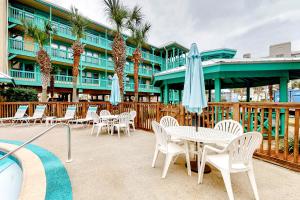 a patio with tables and chairs and a building with palm trees at Sea Breeze #312 in Gulf Shores