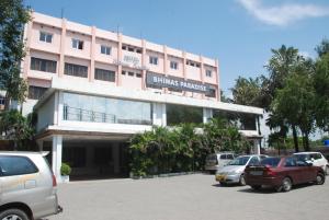 a pink building with cars parked in front of it at Hotel Bhimas Paradise in Tirupati