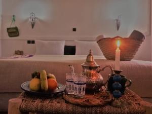 une table avec une assiette de fruits et une bougie dans l'établissement Riad Bleu Afriqua, à Boumalne