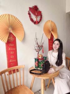 a woman sitting at a table in a room with two chinese signs at LaLa Homestay in Hue