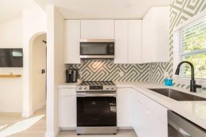 uma cozinha com armários brancos e um forno de fogão preto em The Pastel Home em Fort Lauderdale
