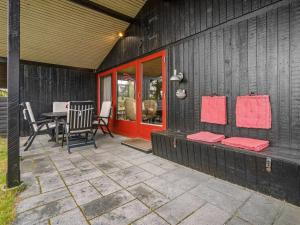 a black house with a patio with a table and chairs at Holiday Home Kathaline - 3-4km from the sea in Western Jutland by Interhome in Bolilmark