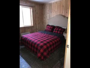 a bedroom with a bed with a plaid blanket and a window at Family Cabin Unit 8 in Rea