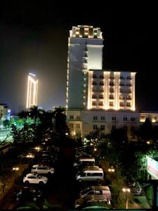 un gran edificio con coches estacionados en un estacionamiento por la noche en LaLa Homestay en Hue