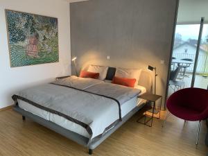 a bedroom with a large bed and a red chair at Trilogie am See Wohnung Taube in Stetten