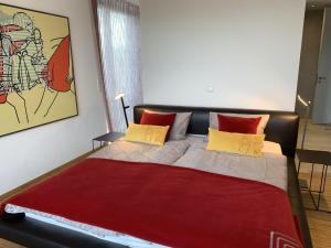 a bedroom with a large bed with red and yellow pillows at Trilogie am See Wohnung Schmetterling in Stetten